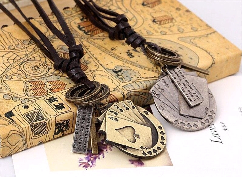Adjustable brown leather cord poker cross necklace with metal pendant flat lay on vintage box