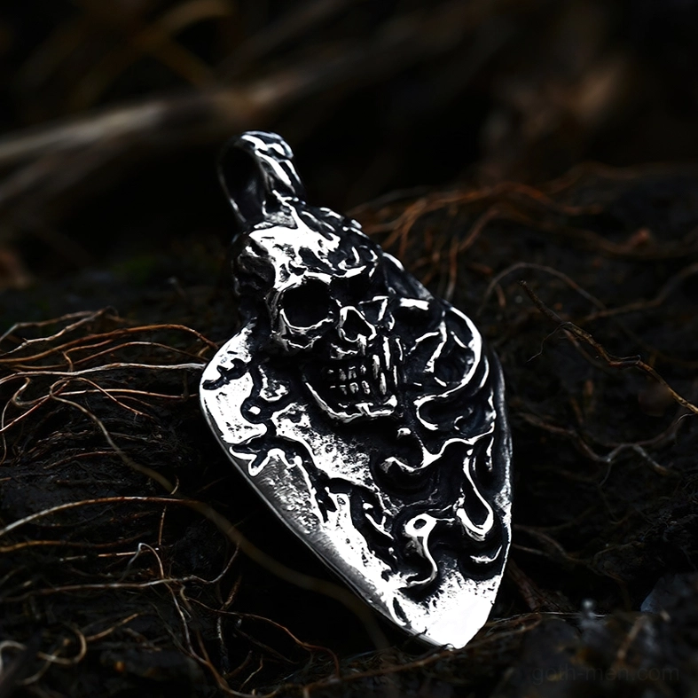 Antique silver engraved skull guitar pick pendant, side close-up with weathered metallic finish