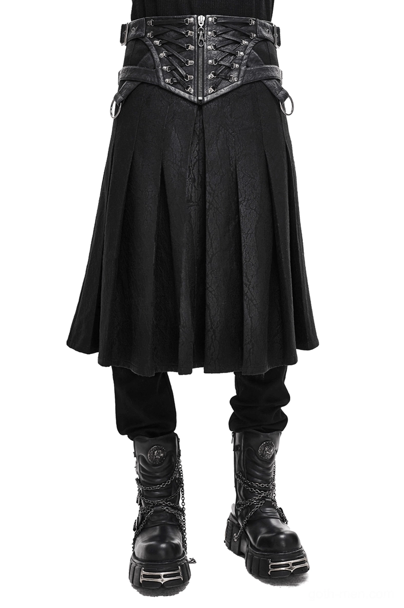 Asymmetric black gothic kilt skirt with buckled leather straps worn by model on white background - front full lower view