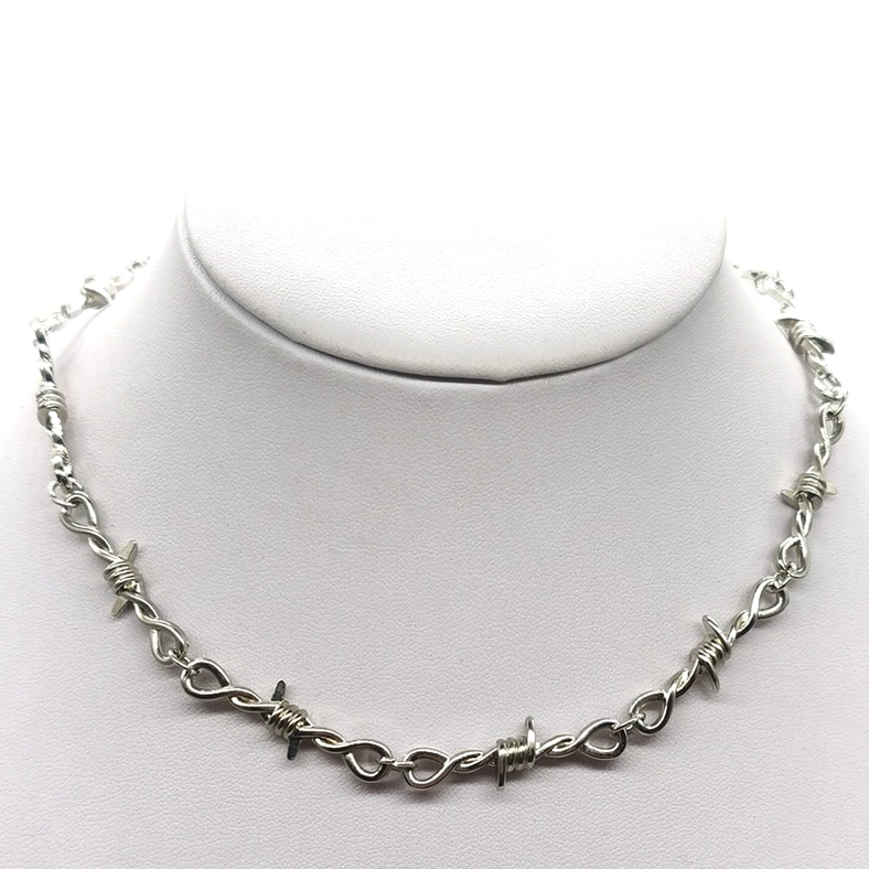 Silver barbed wire gothic choker necklace displayed on white mannequin neck, front close-up view showing detailed thorn chain links and industrial design aesthetic