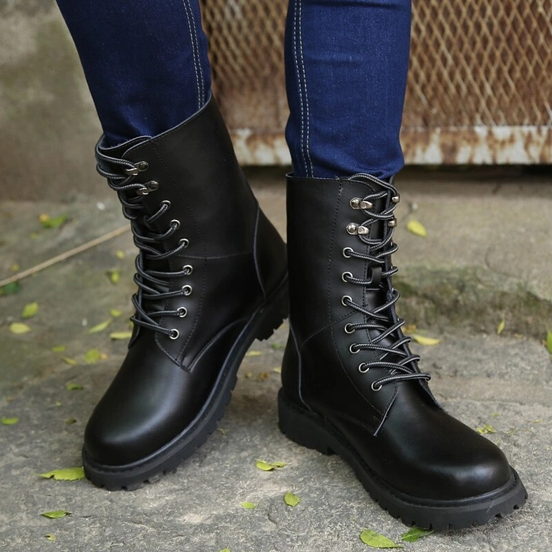 Black combat boots worn with blue jeans photographed from low ground angle, showing classic military boot shape and authentic wear