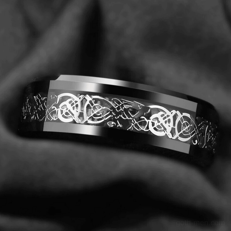 Top-down close-up of gothic dragon ring on dark velvet with polished silver dragon inlay
