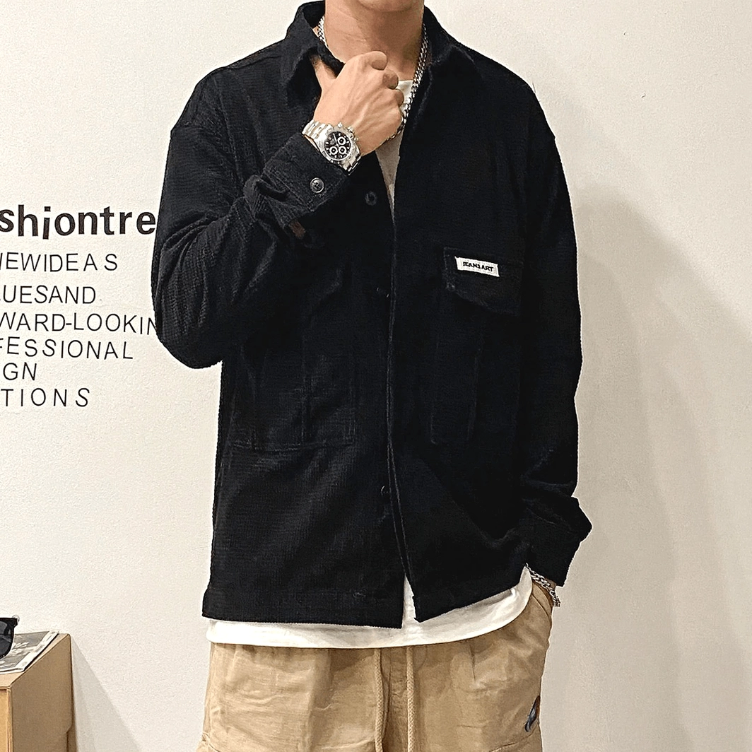 Black corduroy oversized gothic cargo shirt on male model in studio, front close-up view showing button cuffs, layered inner tee, wristwatch, and tactical aesthetic