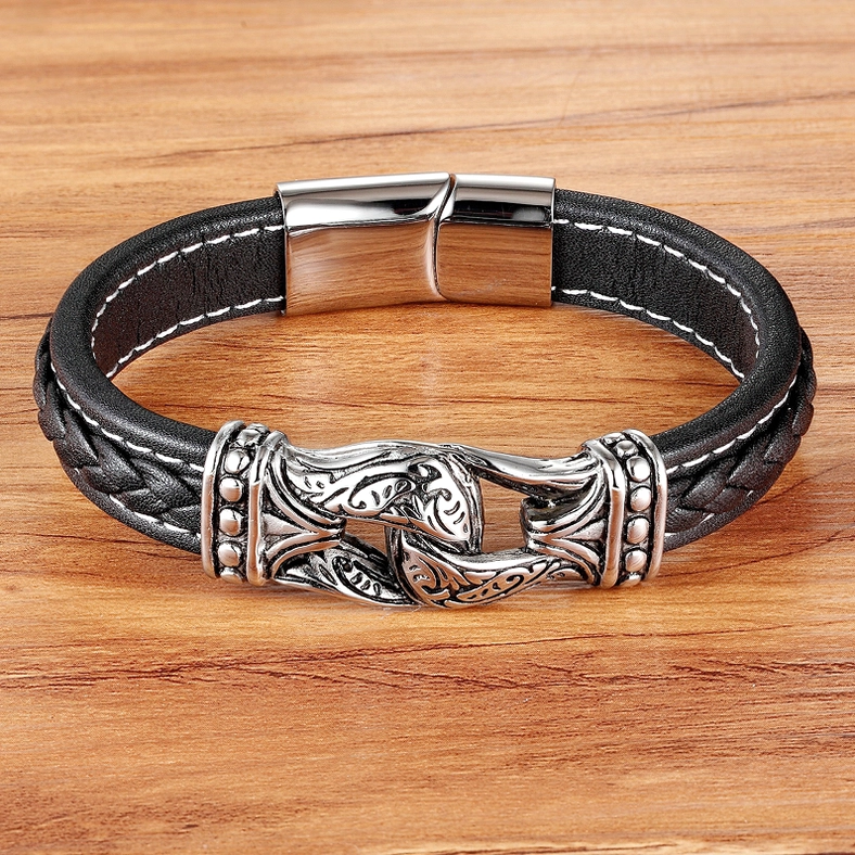 Black leather gothic bracelet with silver stainless steel accents displayed on wooden surface
