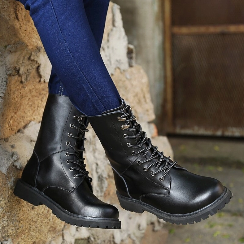Black polished leather high-top combat boots with heavy-duty rubber outsole, side view on concrete outdoor surface