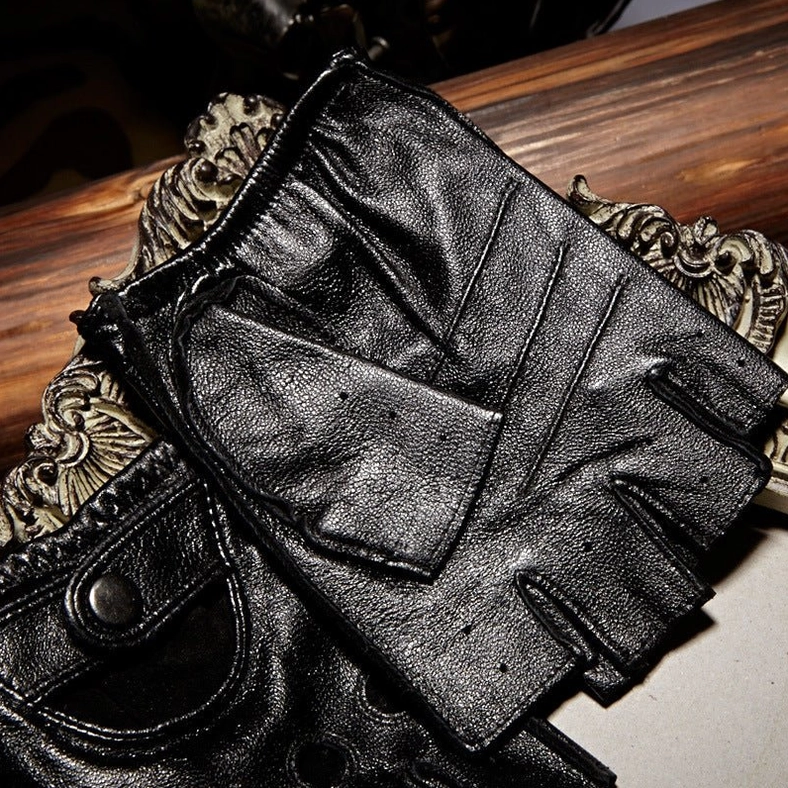 Black polished leather half-finger gloves with snap button, vintage wooden decor background, showing leather grain detail