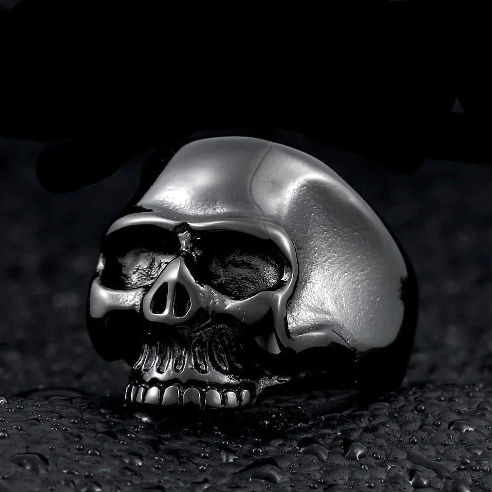 Black gunmetal skull ring front view with high-polished stainless steel, realistic skull carving and sharp details on dark textured surface