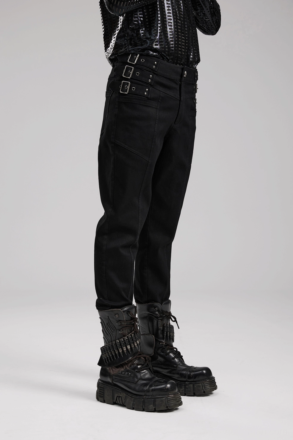 Full-length side view of black studded gothic denim pants demonstrating slim tapered fit