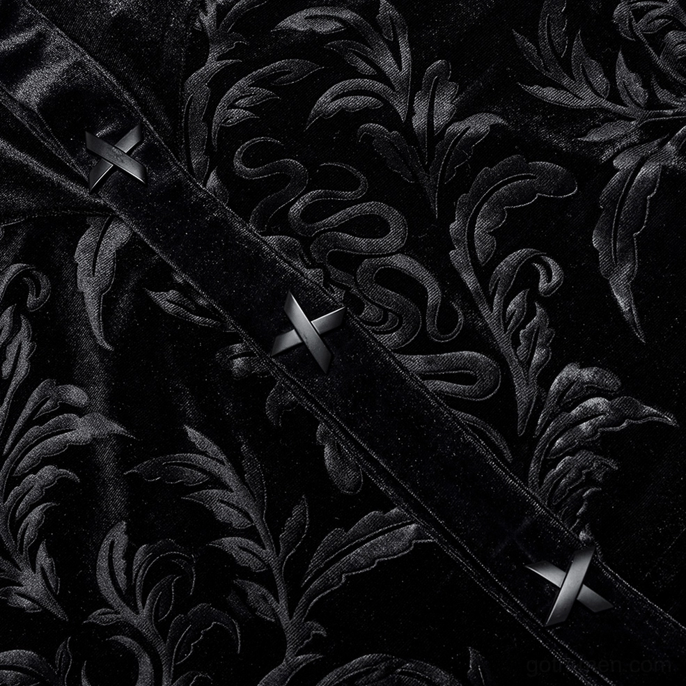 Close-up side view of black velvet gothic shirt placket showing cross-shaped buttons and snake-damask embossed velvet pattern