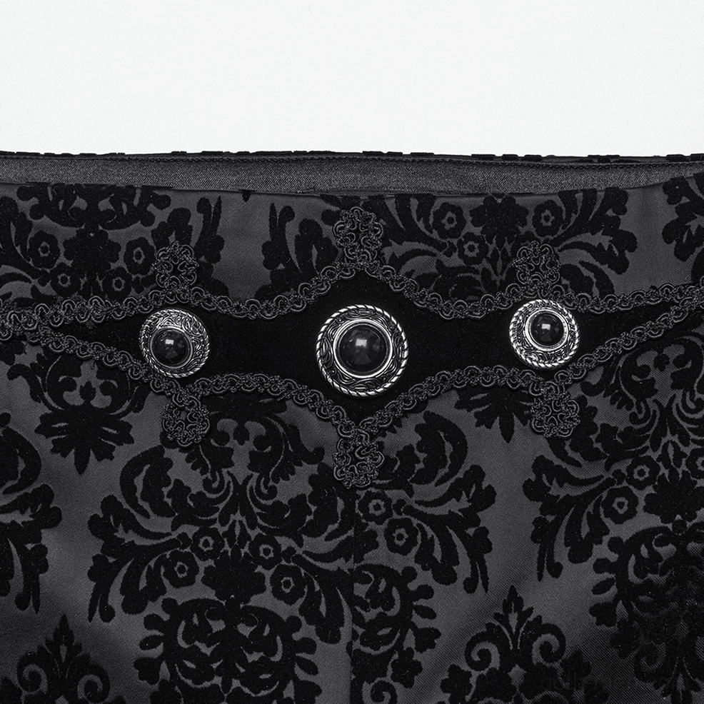 Close-up detail of black velvet pants waistband featuring gem-studded metal buttons velvet trim and damask print