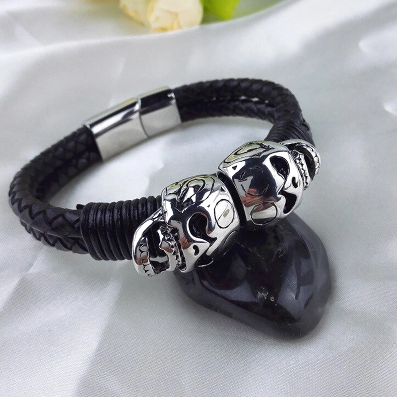 Black braided leather bracelet on fabric surface with silver skull decorations