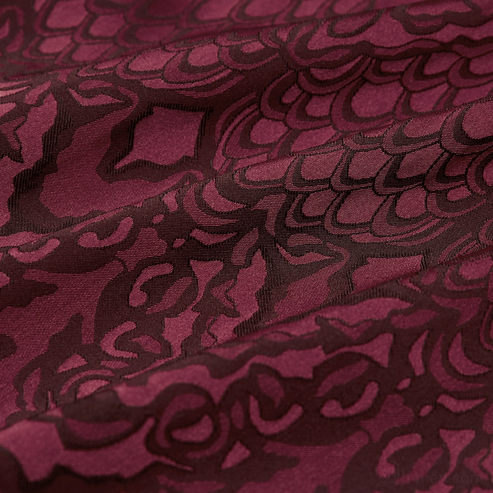 Macro close-up of burgundy gothic jacquard fabric showing intricate floral weave pattern and tonal texture