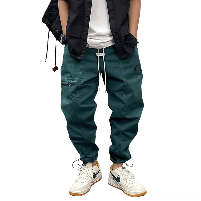 Dark green gothic harem cargo pants front full-body view with drawstring waist and tapered ankle cuffs on male model