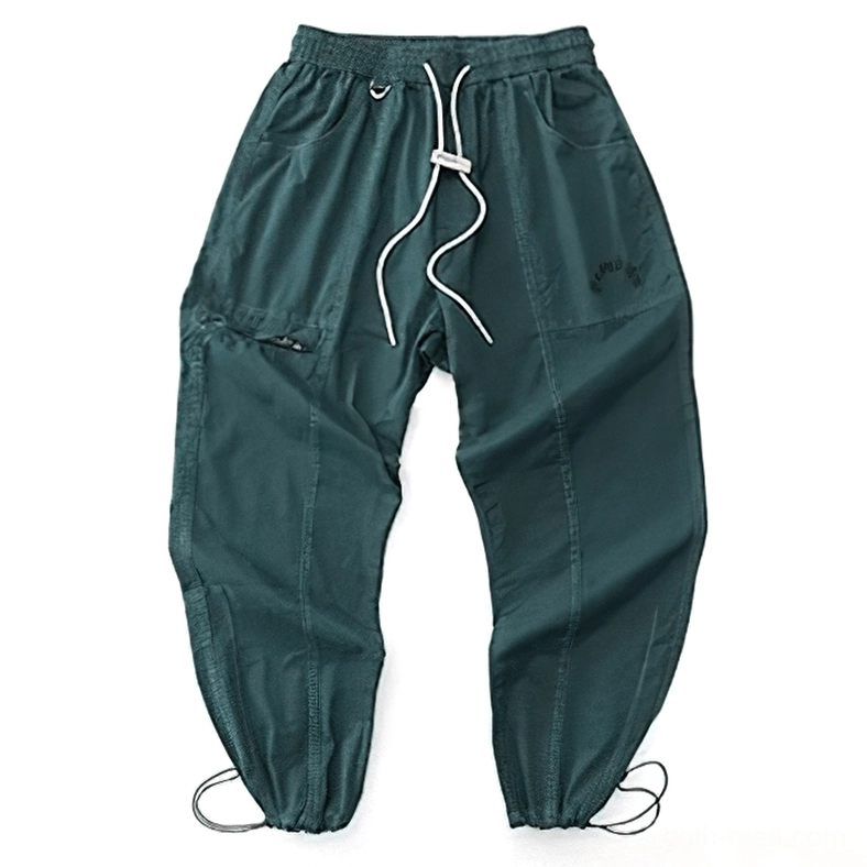 Dark green gothic harem cargo pants flat lay displaying elastic waist, drawstring cuffs, and tapered ankle design