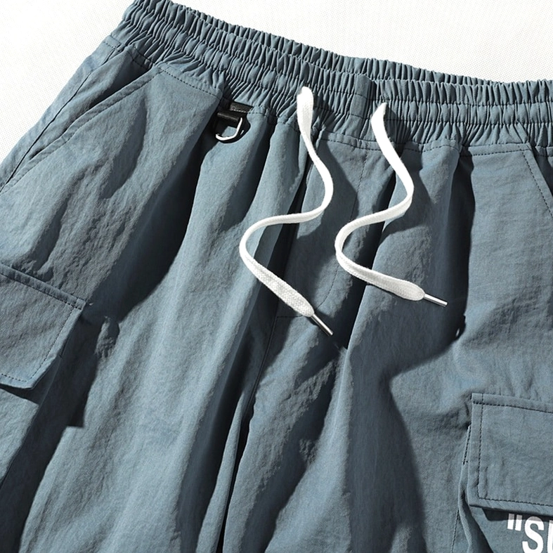 Close-up of dusty blue cargo shorts showing elastic waistband and side pocket construction