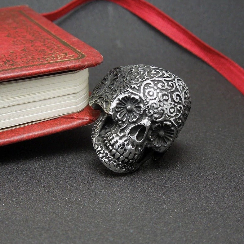 Side-front view of memento mori skull ring with floral decoration, dark surface styling, gothic aesthetic