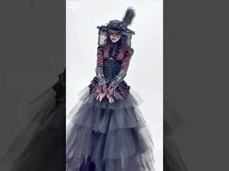 Female gothic model wearing complete dark alternative outfit with black lace-up arm guards and formal goth styling