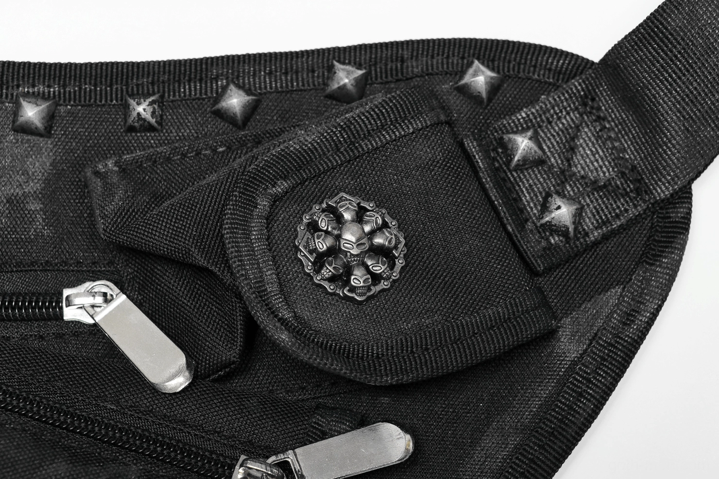 Close-up detail of gothic bag hardware including skull cross emblem, star studs, metal zipper pulls, and rivets
