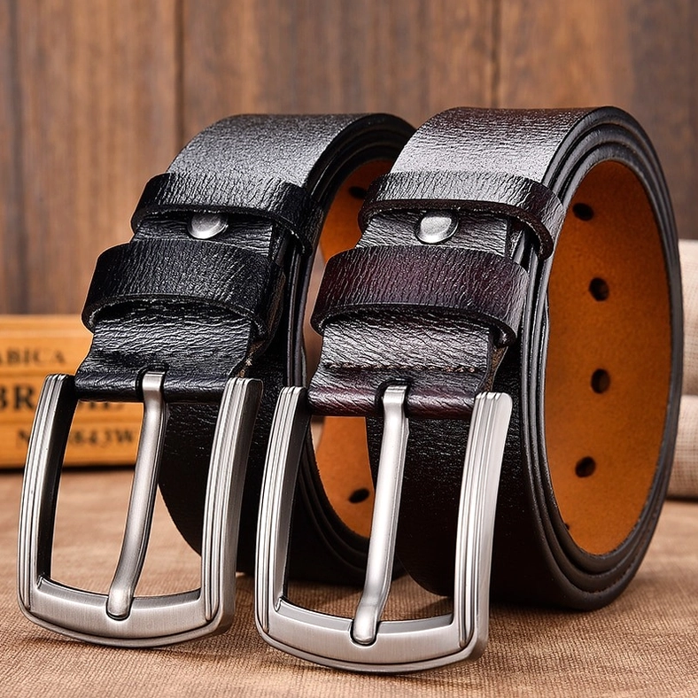 Two unisex gothic leather belts in black and coffee brown with silver buckles on wooden surface