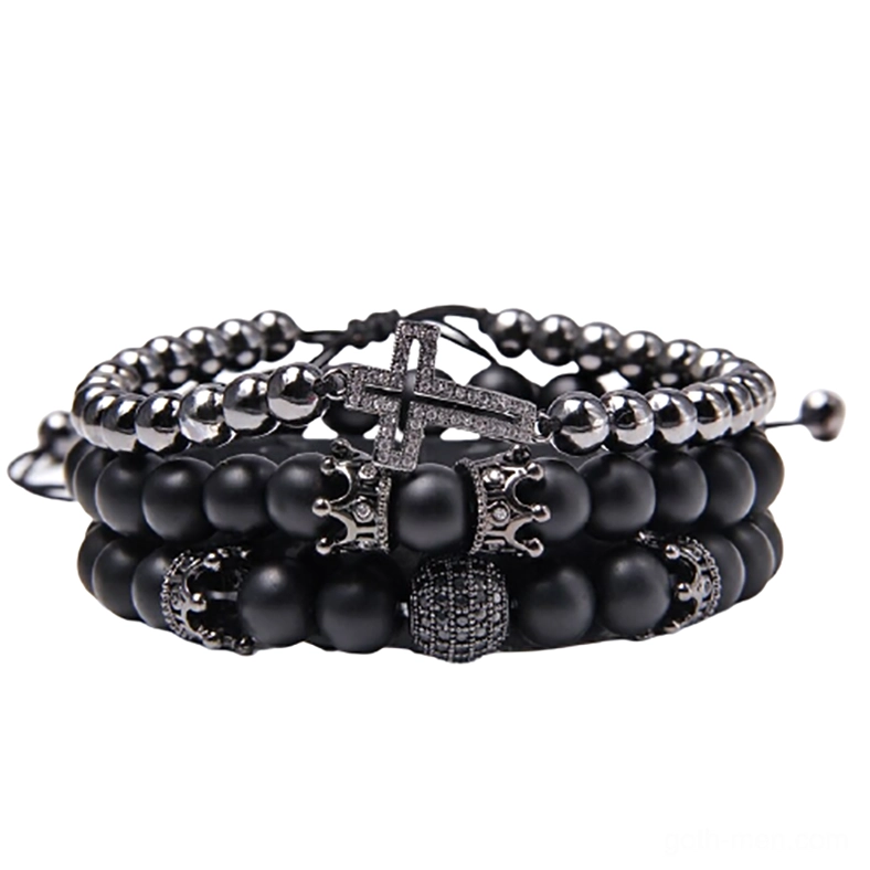 Black gothic charm bracelet set with matte stone beads, ornate cross pendant, and crown charm, flat lay on white background