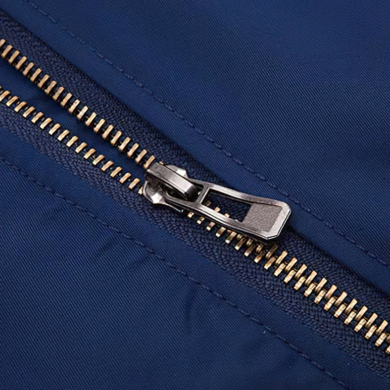 Close-up macro shot of premium gold metal zipper hardware on gothic padded bomber jacket with stitched seams