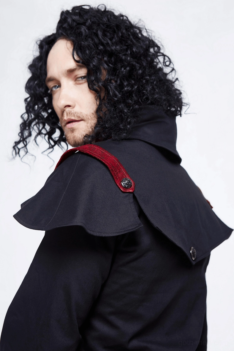 Close-up side view of gothic cape coat shoulder detail on male model, highlighting detachable shoulder pad and red accent strap on black woven fabric