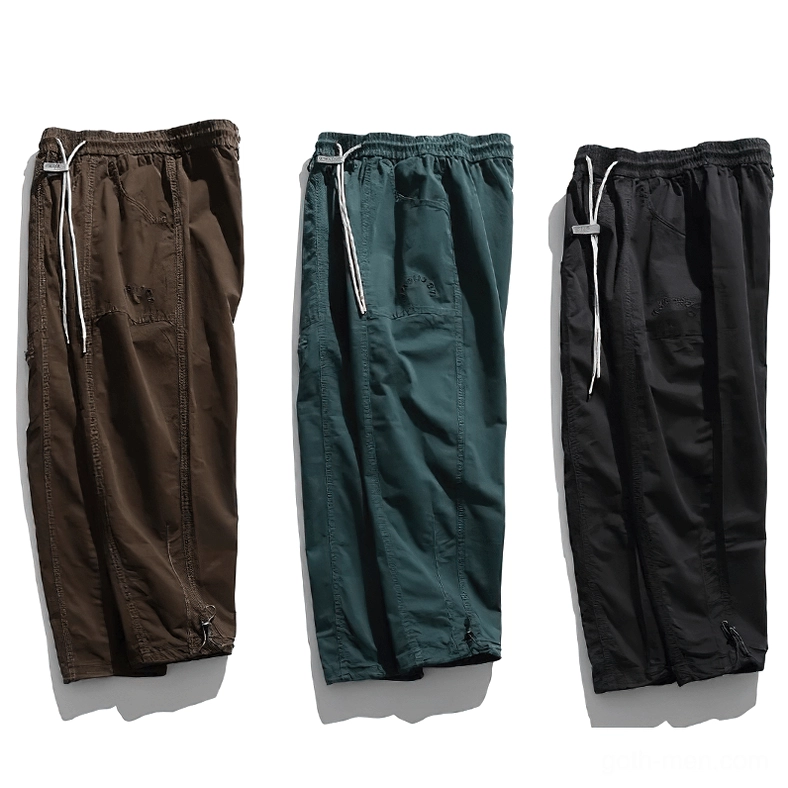 Three folded gothic cargo harem pants in brown, dark green, and black color variants stacked side by side