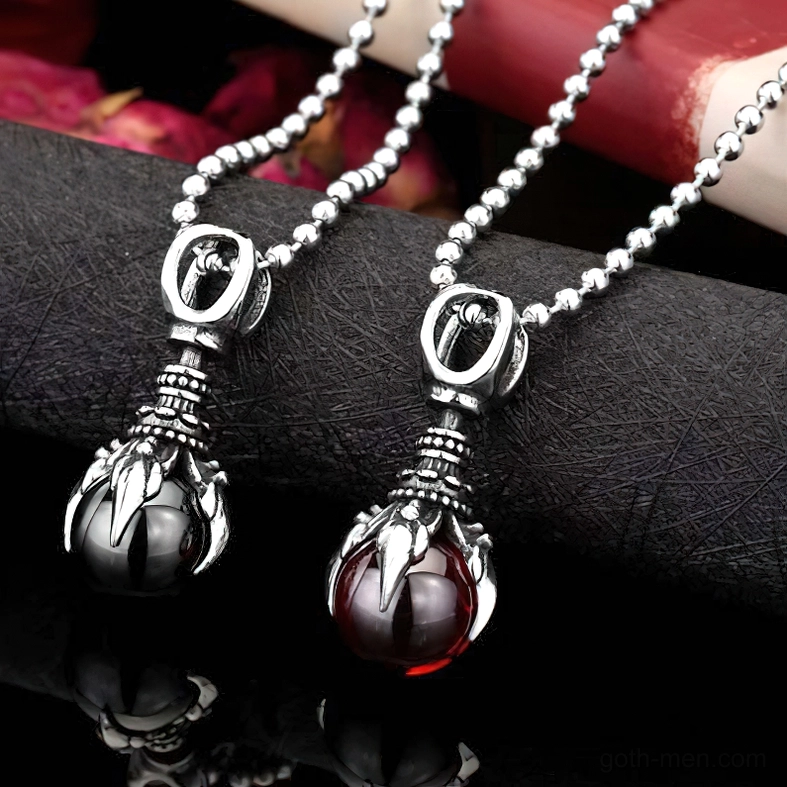 Red and black gothic claw pendants with stainless steel chains on dark floral background