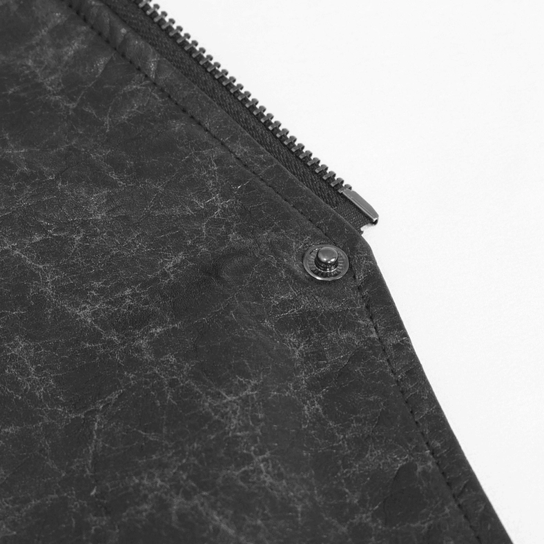 Close-up detail of distressed black faux leather fabric with cracked texture, metal zipper hardware, snap button, and stitched seam accent