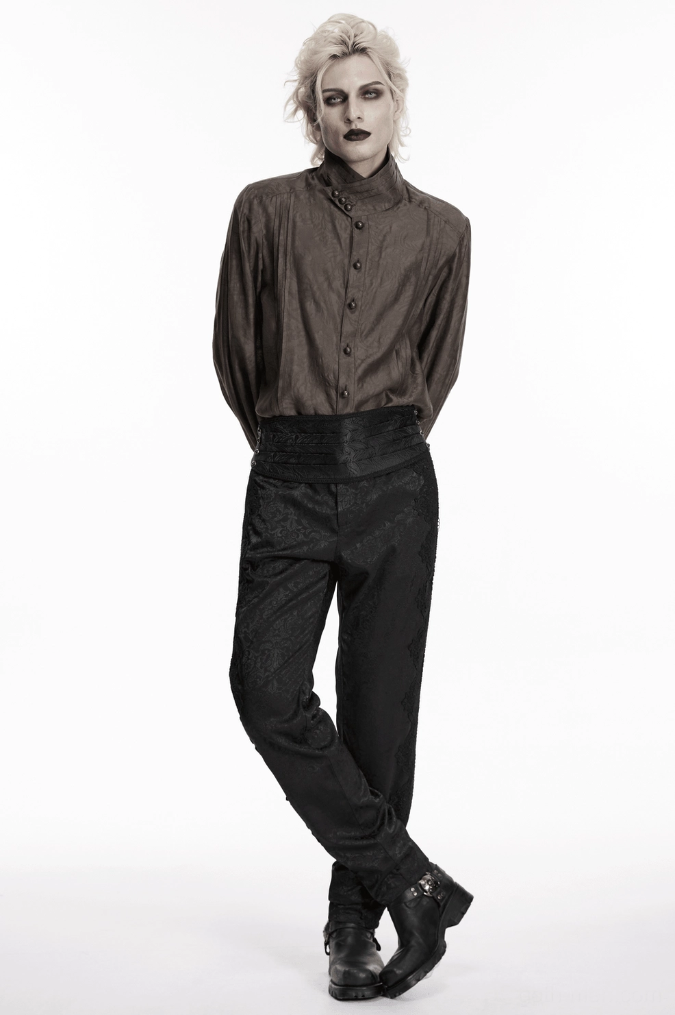 Male model in androgynous styling wearing black jacquard pleated gothic corset belt with high-waisted outfit, full-body side pose against white studio background