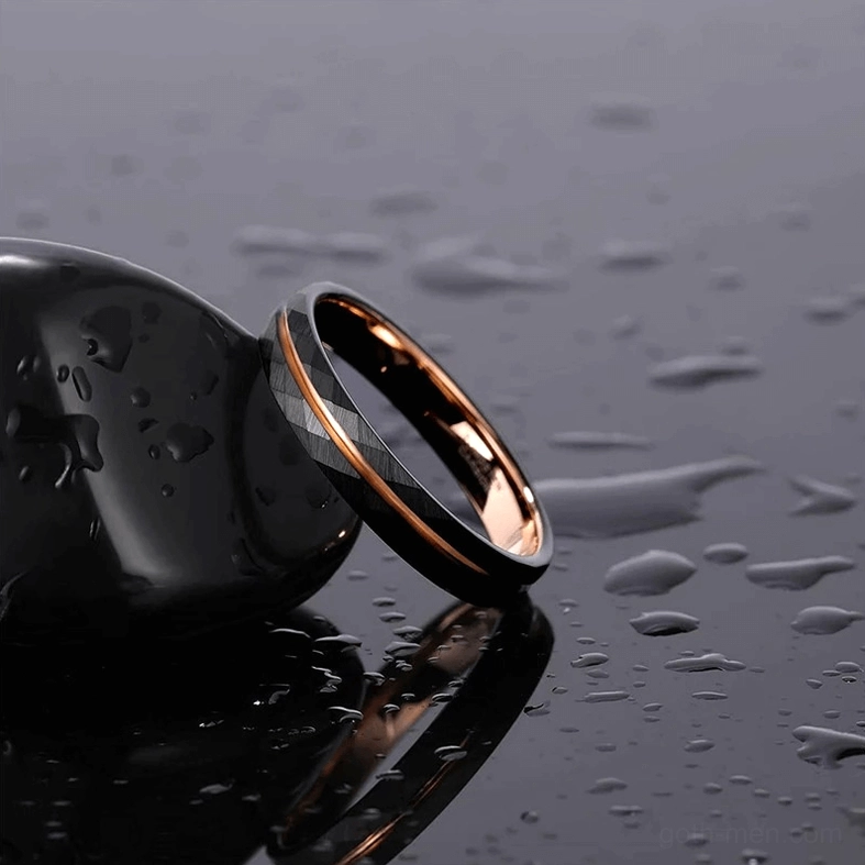 Oblique side view of black tungsten gothic rhombus ring with rose gold accent on water drops