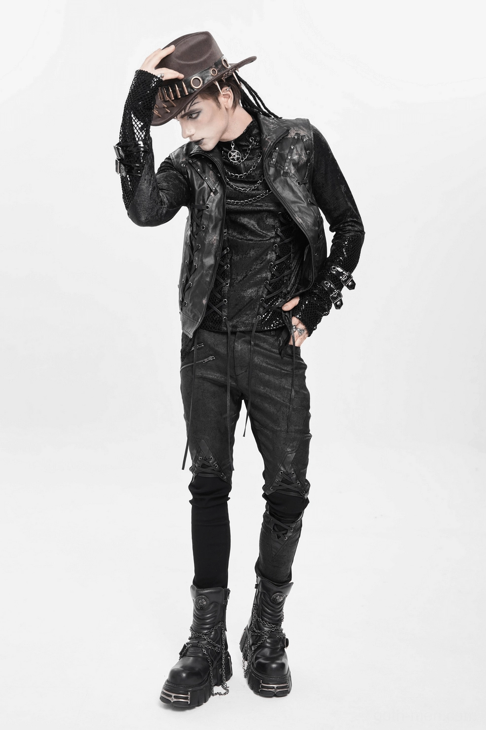 Male goth model front portrait wearing brown gothic cowboy hat with metal bullets and spikes against studio background