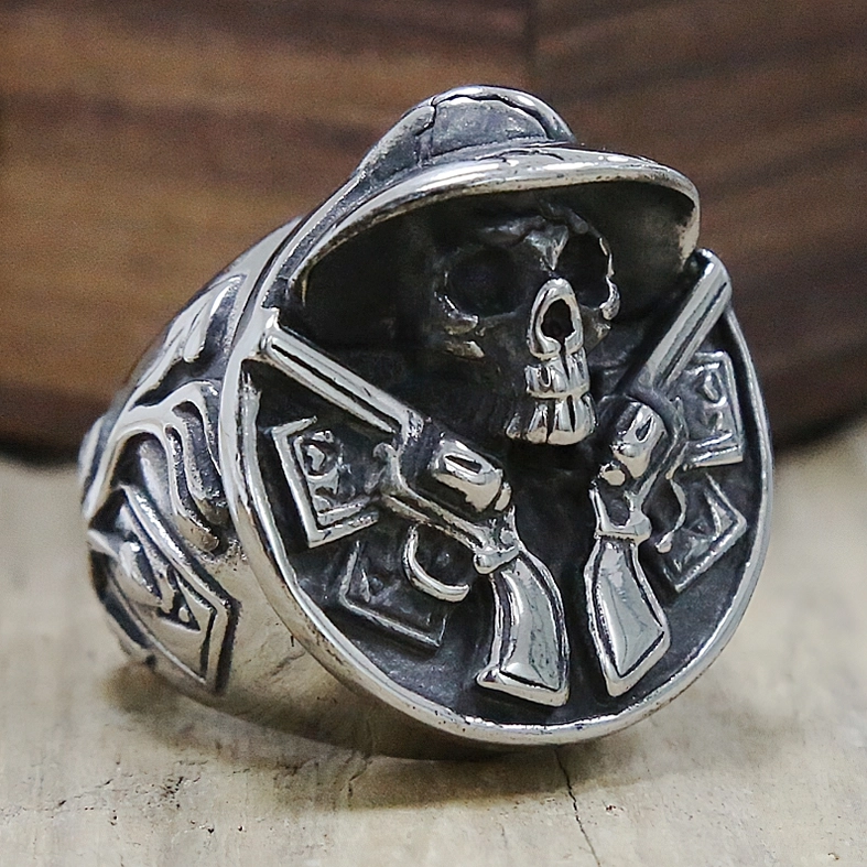Aged silver gothic skull revolver ring oblique angle wooden surface vintage metal texture