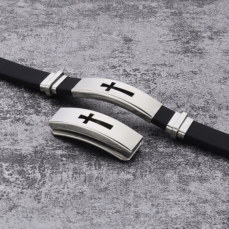 Two gothic cross titanium steel bracelets with spare interchangeable metal plates on textured concrete background
