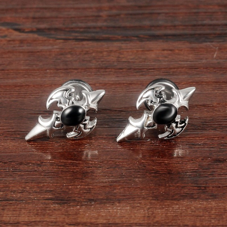 Silver gothic cross stud earrings top-down flat lay on wooden surface - polished finish with black zircon center