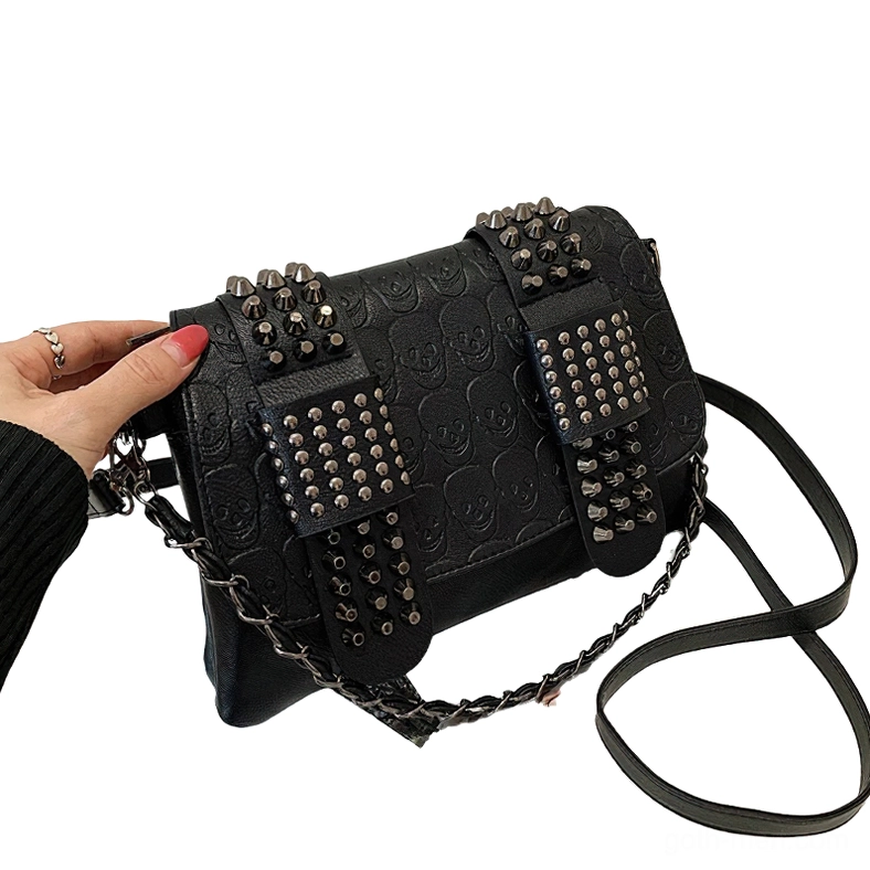 Studded gothic crossbody bag side three-quarter view worn with hand showing dual shoulder strap options