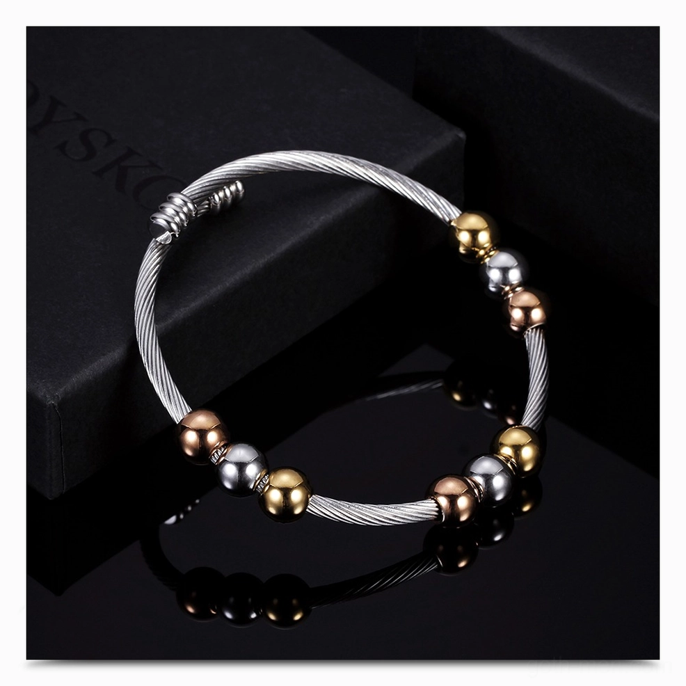 Dark gothic twist cuff bracelet with silver band and metal bead accents on black box