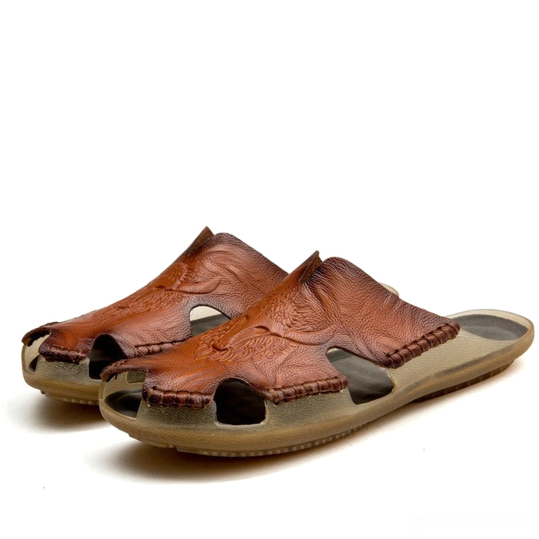 Paired dark reddish brown gothic leather slide sandals with hand-sewn trim and detailed embossed leather work