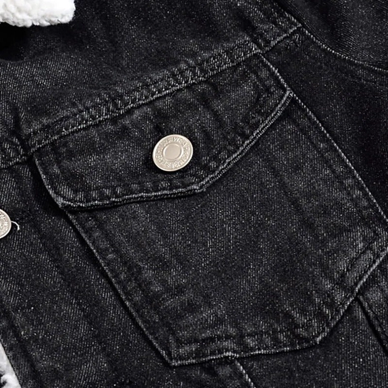 Black denim jacket chest pocket close-up detail showing metal snap button and black denim texture, gothic design element