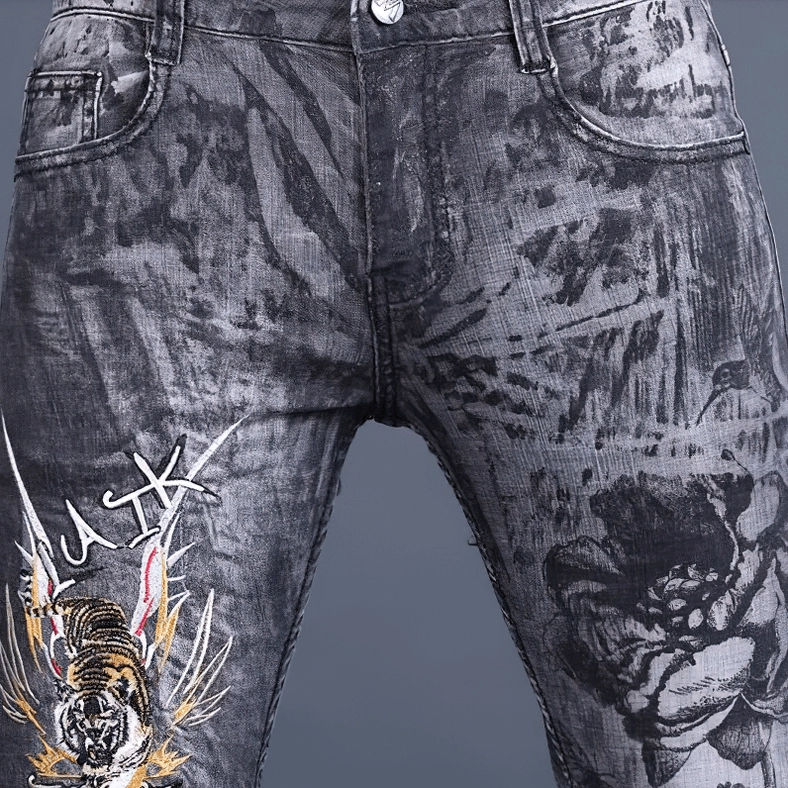 Detail shot of men's gothic embroidered skinny jeans showing dragon and floral embroidery work and denim quality