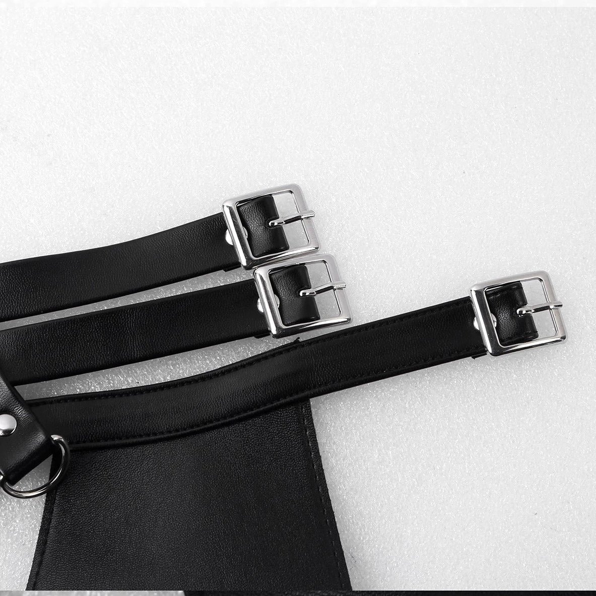 Strap buckle close-up showing silver square buckles, black faux leather, and D-ring accessories on adjustable harness strap