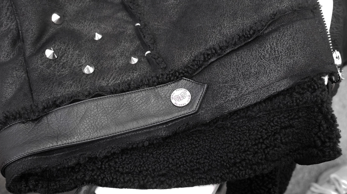 Close-up of gothic jacket cuff with metal snap button and faux shearling lining