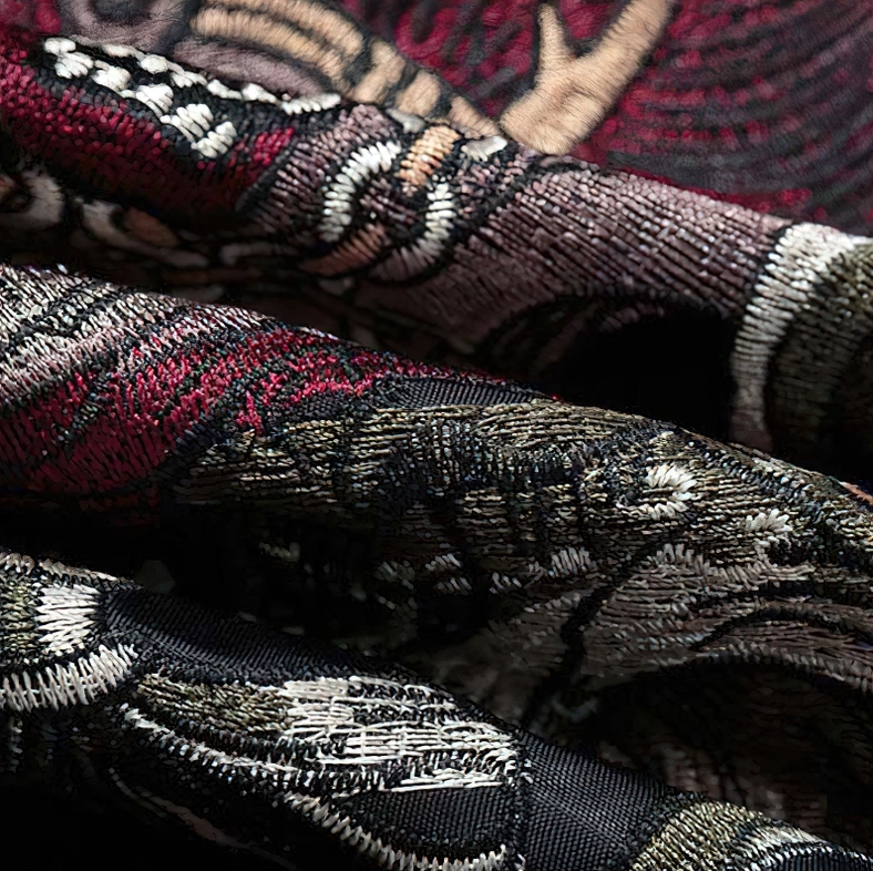 Embroidered fabric texture close-up - intricate multi-pattern stitching and thread details on bomber jacket