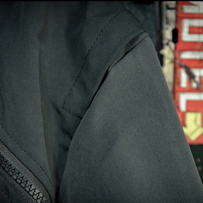 Black gothic jacket sleeve detail showing smooth matte outdoor fabric and overlock stitching craftsmanship