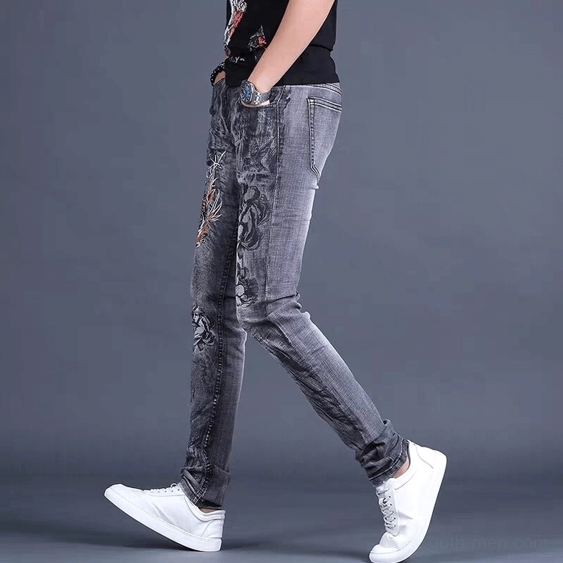 Side profile of men's gothic embroidered denim jeans highlighting slim fit and decorative leg embroidery