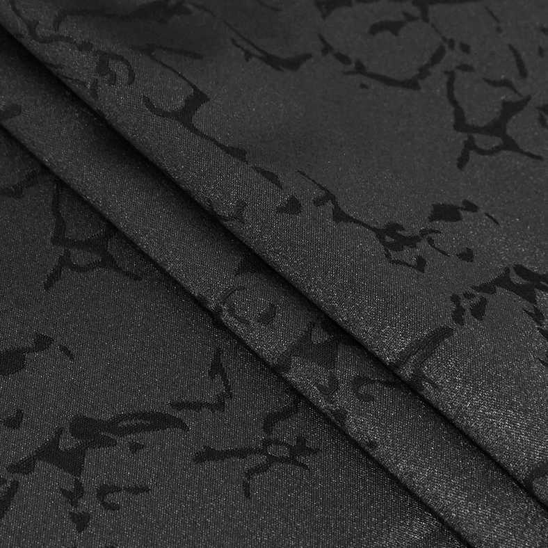Extreme close-up of black gothic pants fabric showing shiny crack-like jacquard pattern and intricate weaving