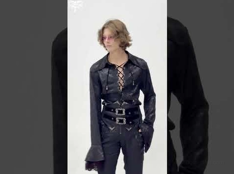 Black gothic lace-up shirt styled with waist belt on male model demonstrating alternative fashion