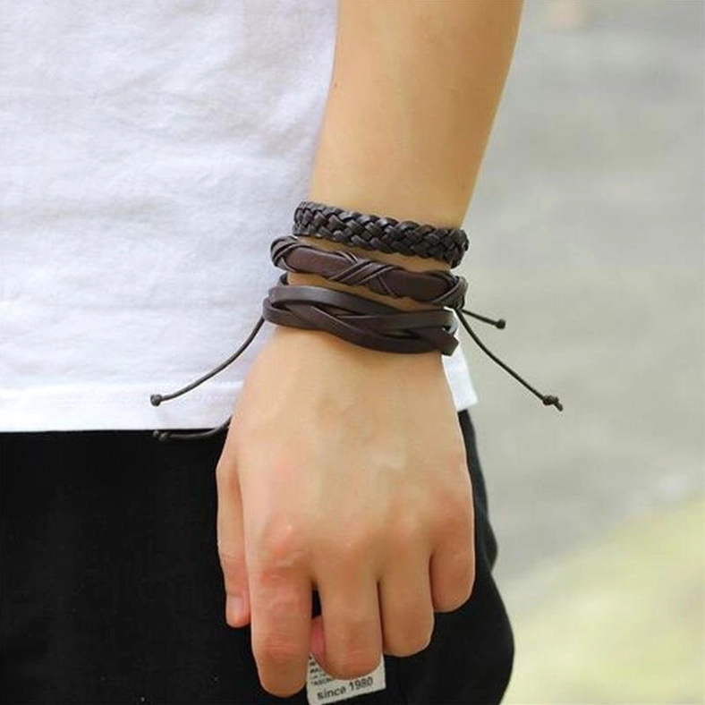 Male model wearing layered dark brown leather gothic bracelets on wrist outdoor casual street style