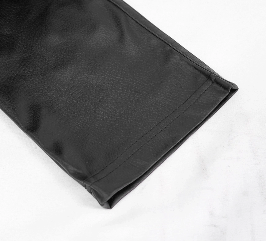Side close-up detail of black gothic leather pants hem showing stitched plain hem edge and smooth PU leather fabric surface