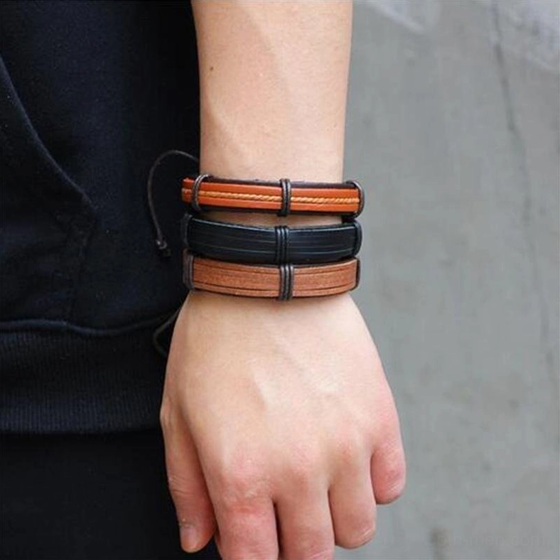 Male model wearing dual brown and black leather gothic bracelets with mixed tone layered design on wrist